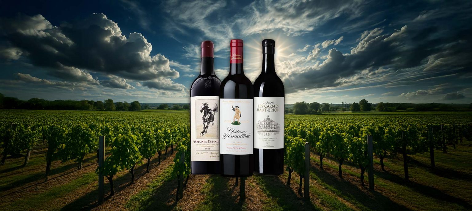 Three Bordeaux red wines—Domaine de Chevalier 2022, Château d'Armailhac, and Château Les Carmes Haut-Brion 2022—standing in front of a dramatic vineyard landscape with cloudy skies and sunbeams breaking through.
