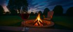 Glass of red wine by a backyard fire put at dusk