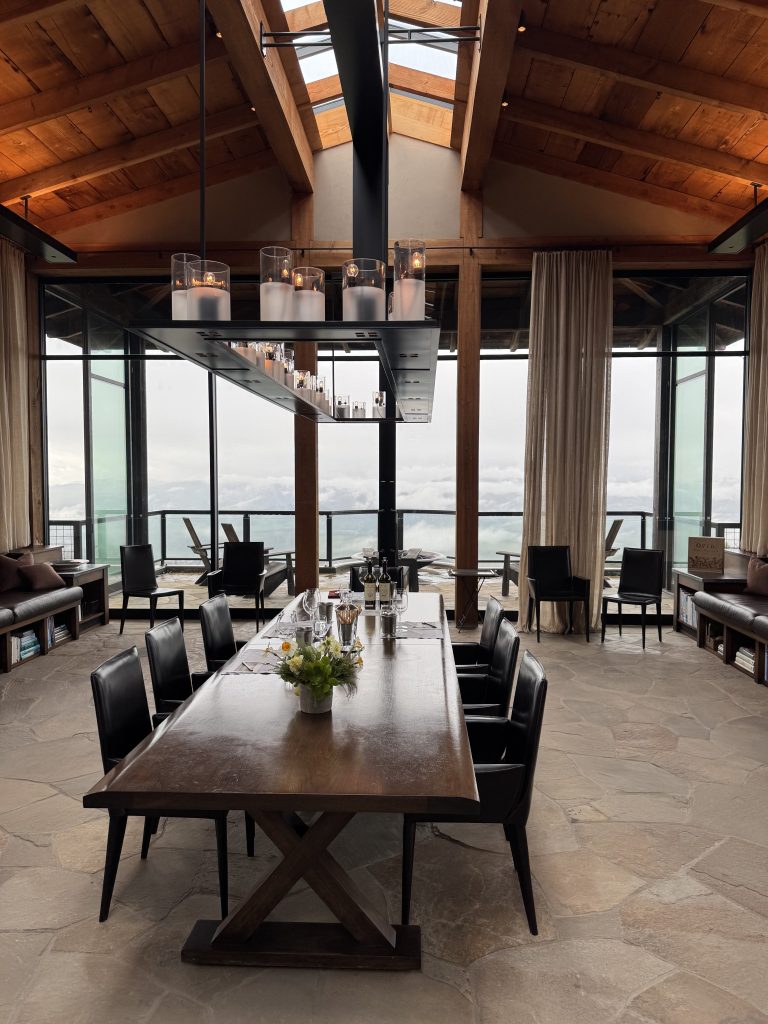 OVID Winery tasting room interior with soaring glass walls, wood-beamed ceiling, and long tables set for a private wine tasting on Pritchard Hill