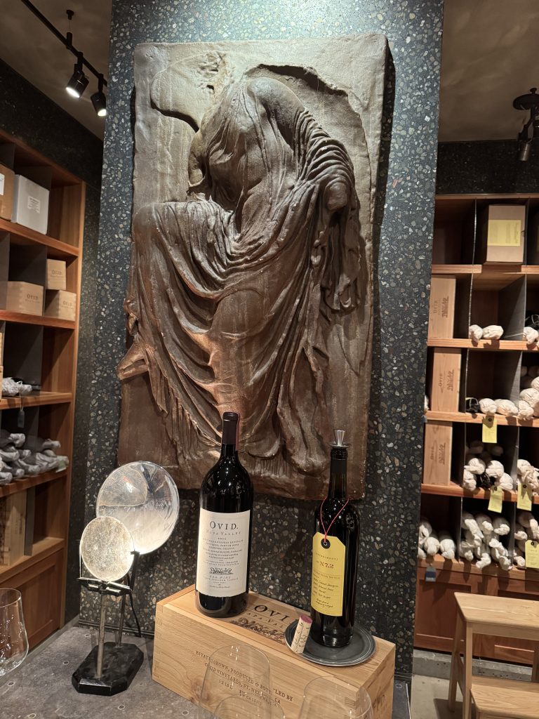 Two bottles of OVID wine displayed on a stone relief sculpture in the tasting room, alongside a crystal decanter