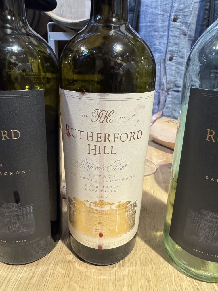 Rutherford Hill "Heaven's Peak" Estate Cabernet Sauvignon 2022, Rutherford Napa Valley, displayed among other wine bottles on a wooden table