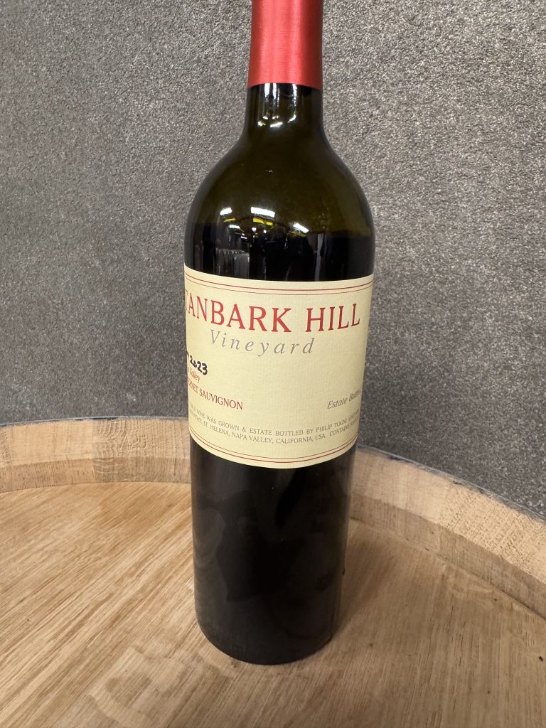 Bottle of Tanbark Hill Vineyard wine resting on an oak barrel at Philip Togni Winery, Napa Valley