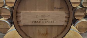 Close-up of a new oak barrel head stamped with the Château Lynch-Bages name and cooperage marking in the barrel room