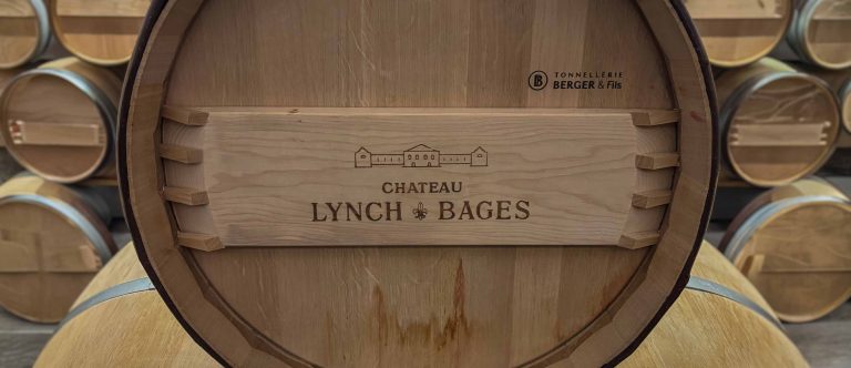 Close-up of a new oak barrel head stamped with the Château Lynch-Bages name and cooperage marking in the barrel room