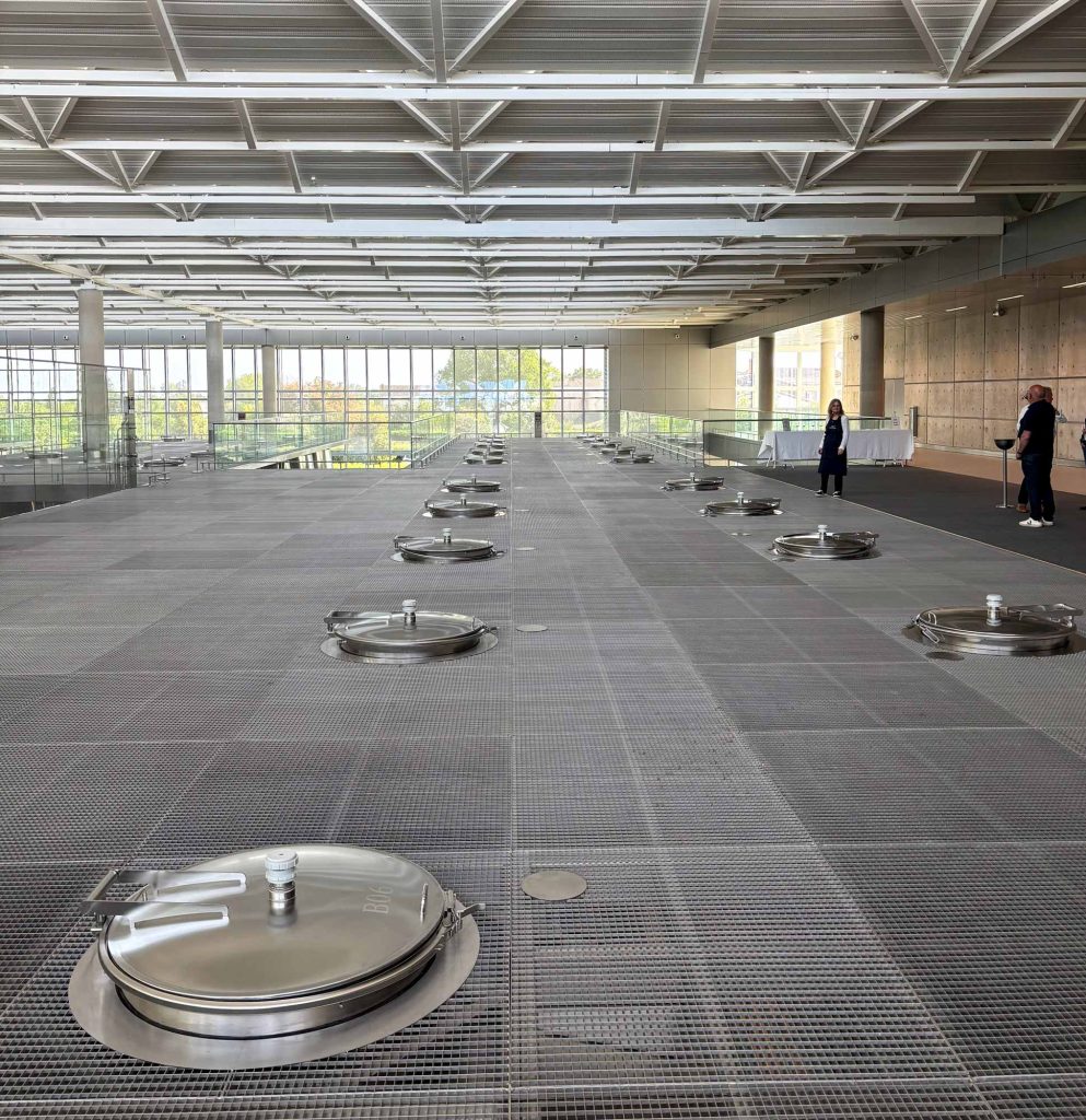 Full-length view down the new Lynch-Bages tank hall with the geometric skylight on one side and stainless tank hatches on the other
